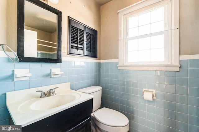 bathroom with vanity, tile walls, and toilet