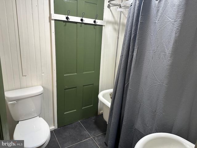 bathroom with wooden walls, tile patterned floors, and toilet