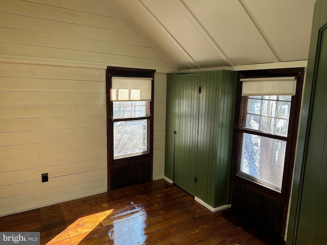 entryway with lofted ceiling, dark hardwood / wood-style floors, and wooden walls