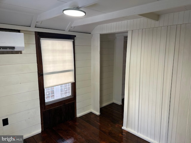 spare room featuring beamed ceiling, wood walls, dark hardwood / wood-style floors, and an AC wall unit