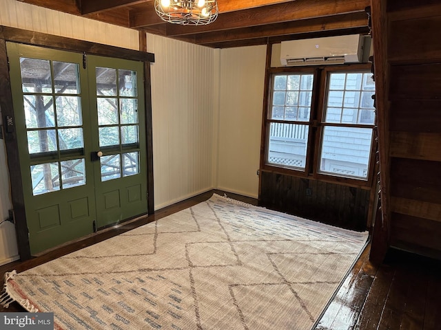 foyer entrance with dark hardwood / wood-style floors, a wall mounted AC, a notable chandelier, beam ceiling, and french doors