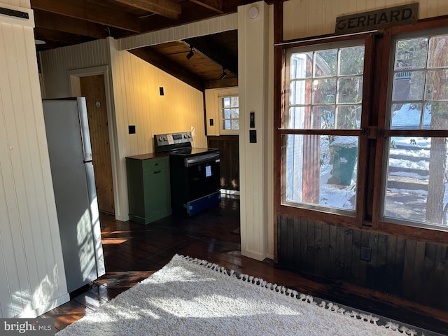 kitchen featuring beamed ceiling, appliances with stainless steel finishes, wooden walls, and dark hardwood / wood-style flooring