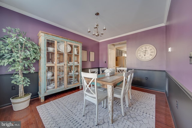 dining area featuring ornamental molding, a chandelier, and dark hardwood / wood-style flooring