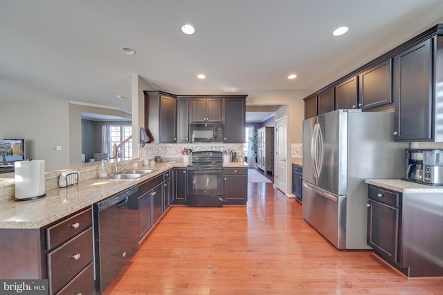 kitchen with sink, backsplash, black appliances, dark brown cabinets, and light wood-type flooring