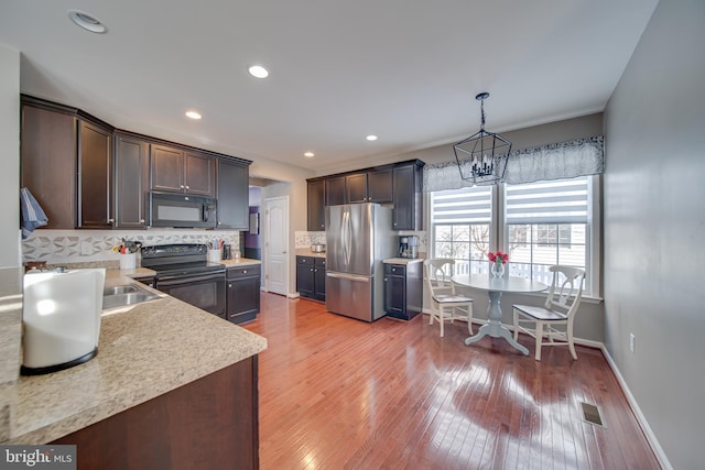 kitchen featuring pendant lighting, backsplash, dark brown cabinetry, and black appliances