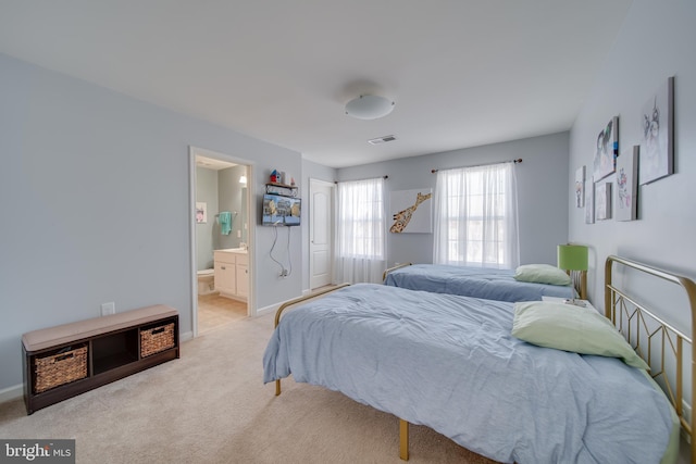 bedroom featuring ensuite bathroom and light colored carpet