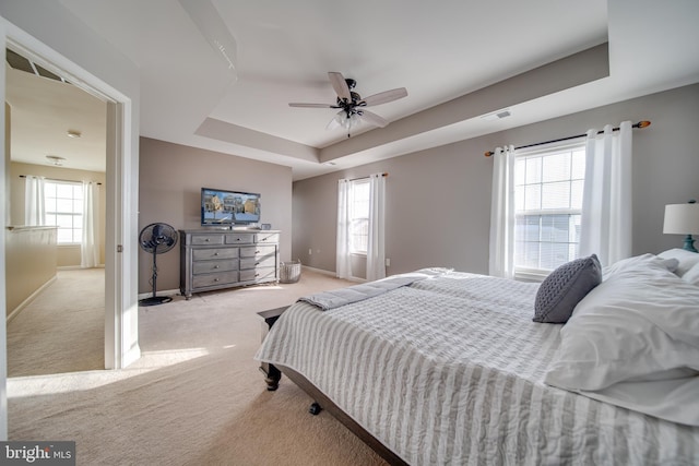 carpeted bedroom featuring ceiling fan and a tray ceiling