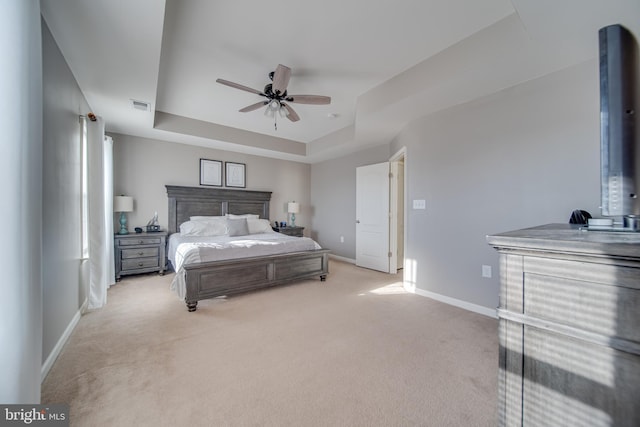 carpeted bedroom featuring a raised ceiling and ceiling fan