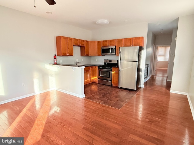 kitchen with sink, stainless steel appliances, dark hardwood / wood-style floors, and kitchen peninsula