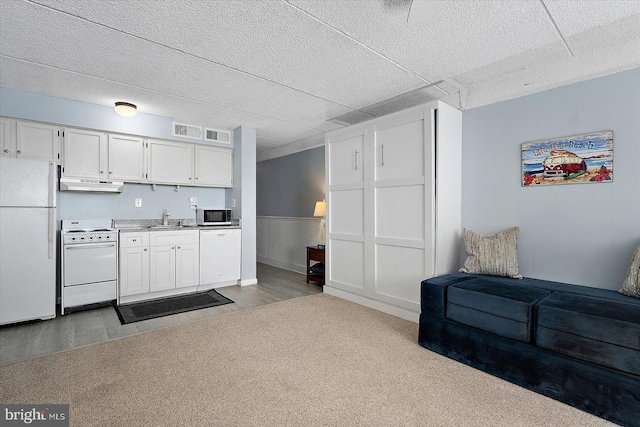 kitchen featuring white cabinetry, dark carpet, white appliances, and sink