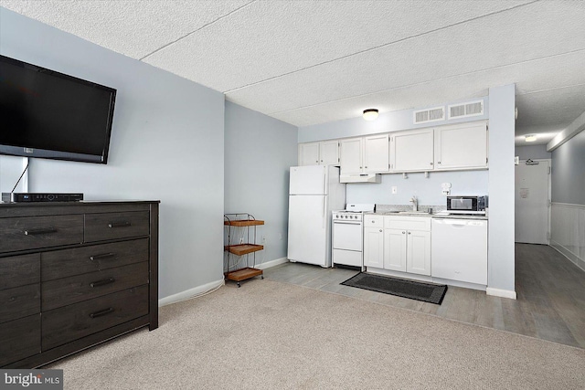 kitchen featuring dark brown cabinetry, white cabinetry, light colored carpet, and white appliances