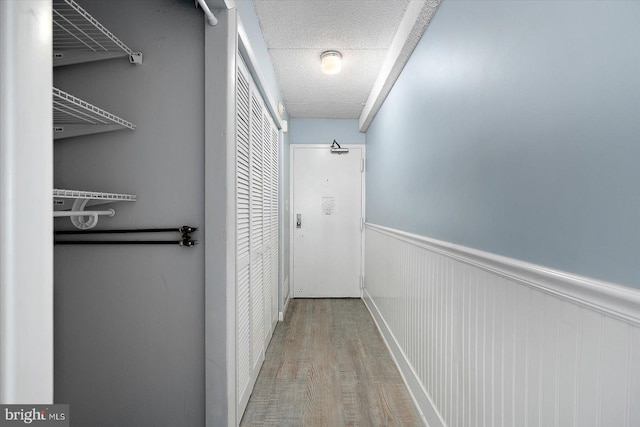 hall with a textured ceiling and light wood-type flooring