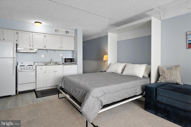 bedroom featuring sink, light hardwood / wood-style floors, and white refrigerator