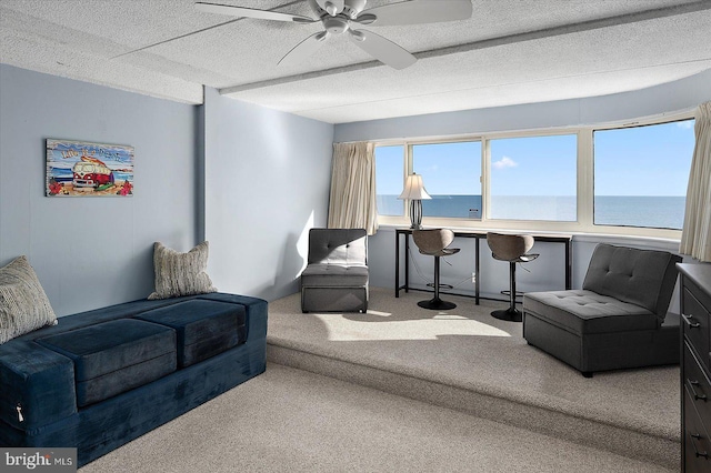 carpeted living room with a water view, ceiling fan, and a textured ceiling