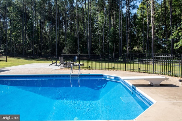 view of pool featuring a diving board, a lawn, and a patio area