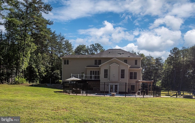 rear view of property with a pool and a yard