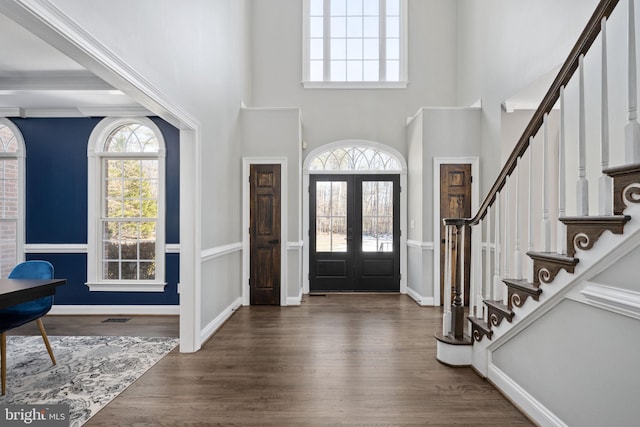 entryway with a towering ceiling, dark wood-type flooring, and french doors