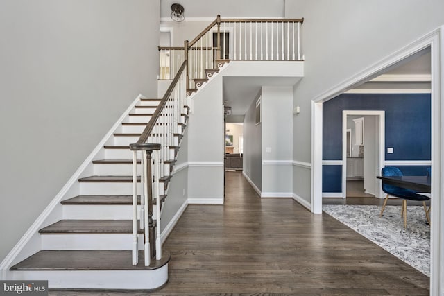 stairs with hardwood / wood-style flooring and a high ceiling