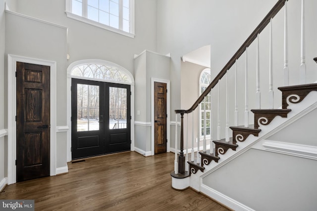 foyer featuring plenty of natural light, a towering ceiling, dark hardwood / wood-style flooring, and french doors