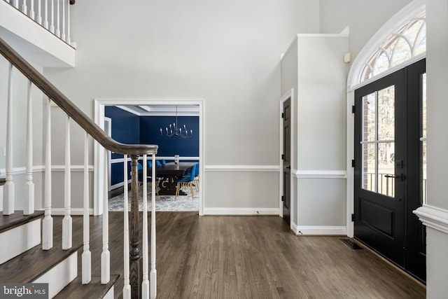 entryway featuring an inviting chandelier, a towering ceiling, and wood-type flooring