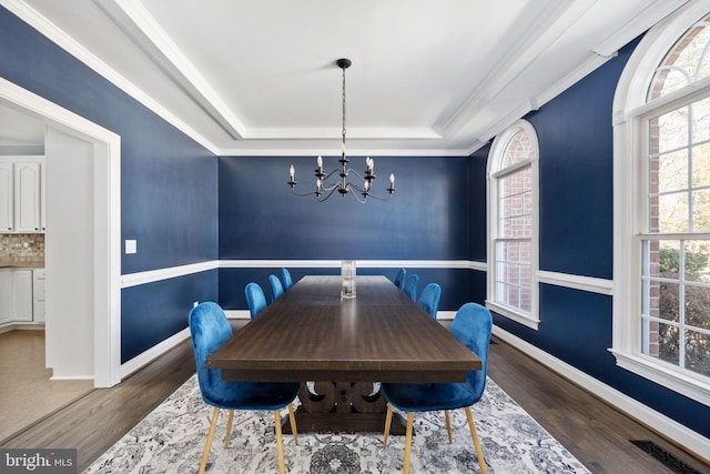 dining room featuring a raised ceiling, dark wood-type flooring, and a chandelier