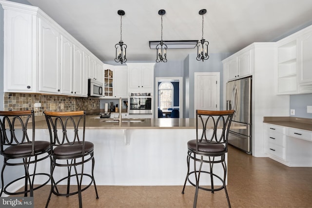 kitchen featuring sink, white cabinets, a kitchen bar, kitchen peninsula, and stainless steel appliances