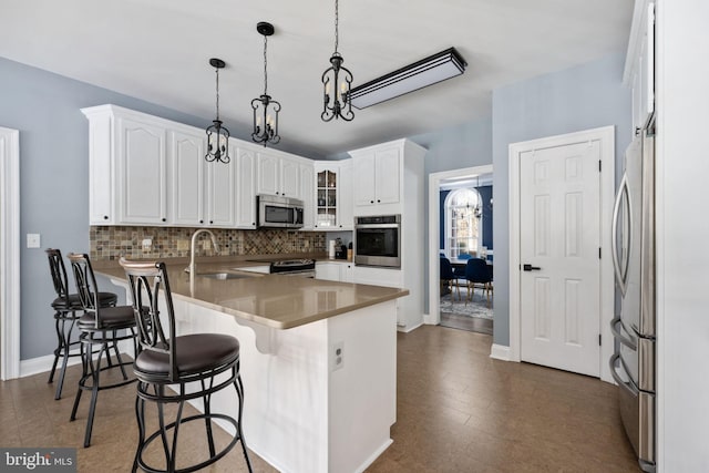 kitchen with sink, stainless steel appliances, a breakfast bar, and white cabinets