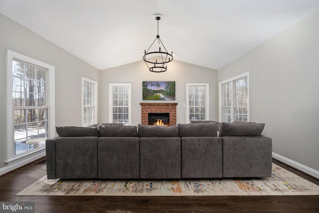 living room with an inviting chandelier, a fireplace, lofted ceiling, and dark hardwood / wood-style floors