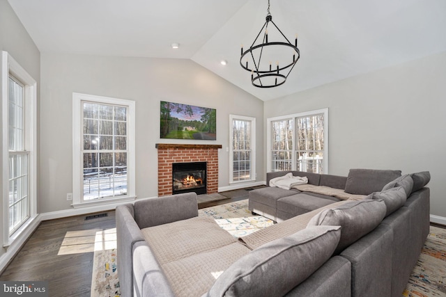 living room featuring a wealth of natural light, vaulted ceiling, dark hardwood / wood-style floors, and a chandelier