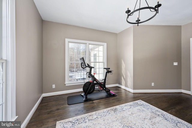 exercise room featuring dark wood-type flooring and a chandelier