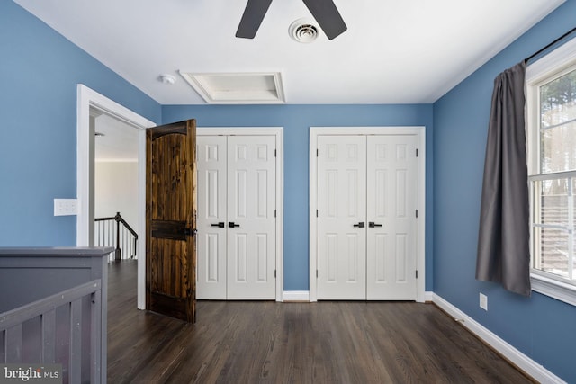 unfurnished bedroom with multiple closets, ceiling fan, and dark hardwood / wood-style flooring