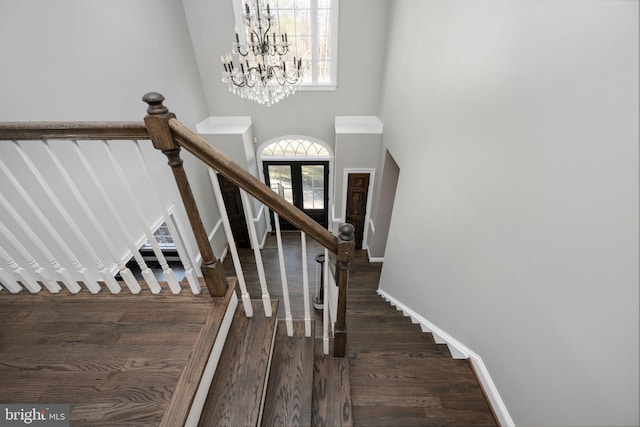 stairway with an inviting chandelier, hardwood / wood-style floors, and a high ceiling