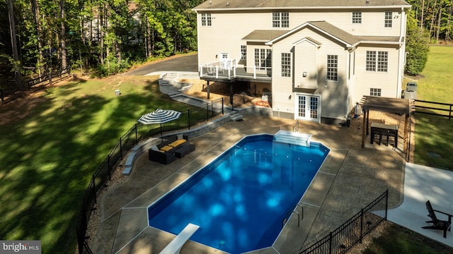 rear view of house featuring a patio, a yard, french doors, and a fenced in pool