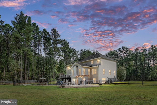 back house at dusk with a yard and a patio area