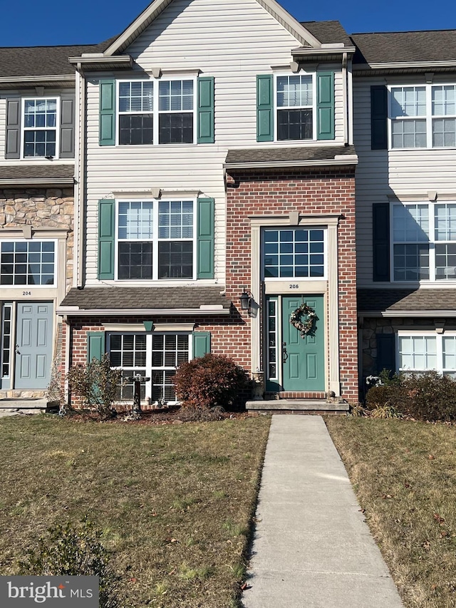 view of property featuring a front lawn and brick siding