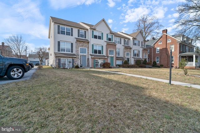 multi unit property with a residential view, stone siding, and a front yard