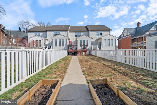 rear view of house featuring a garden, a residential view, and a fenced backyard