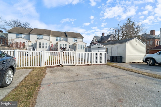 view of front facade with a residential view, fence, an outbuilding, and a storage unit