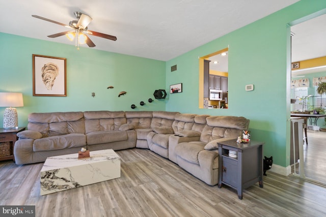 living room featuring baseboards, ceiling fan, visible vents, and wood finished floors