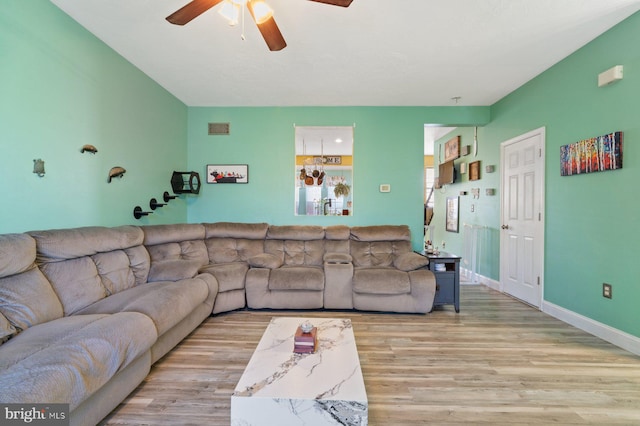 living room with wood finished floors, a ceiling fan, and baseboards