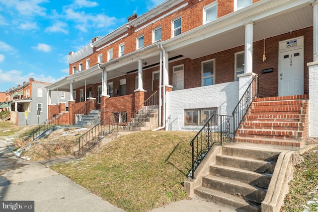 view of property with covered porch and a front lawn