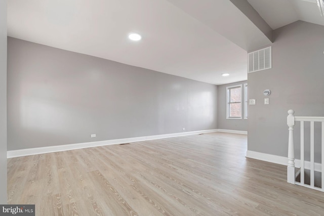 spare room featuring vaulted ceiling and light hardwood / wood-style floors