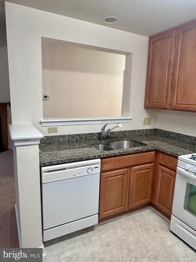 kitchen featuring sink, white appliances, dark stone counters, and light tile patterned floors