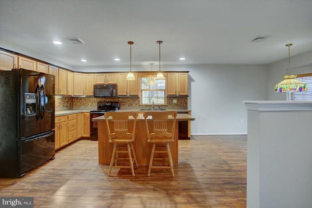 kitchen featuring a center island, sink, light wood-type flooring, and black appliances