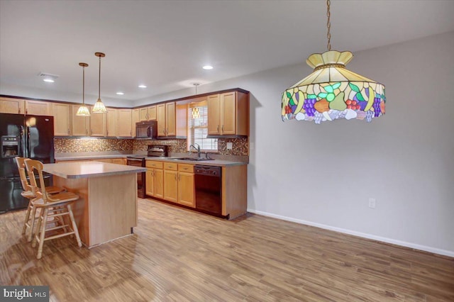 kitchen featuring a kitchen island, decorative light fixtures, backsplash, and black appliances