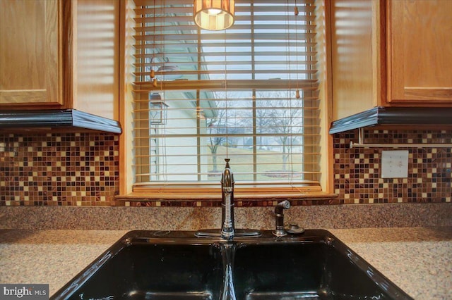 kitchen with sink, decorative backsplash, and light stone countertops