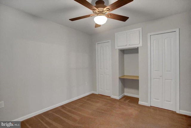 unfurnished bedroom featuring ceiling fan, light colored carpet, and two closets