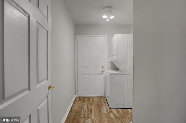 clothes washing area featuring light hardwood / wood-style floors and stacked washer / dryer