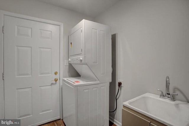 laundry area featuring stacked washer / drying machine and sink