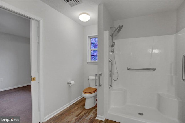 bathroom with walk in shower, toilet, and hardwood / wood-style flooring